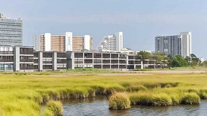 Un ensemble immobilier moderne composé de plusieurs bâtiments, entouré d’une zone verdoyante et d’un petit plan d’eau.