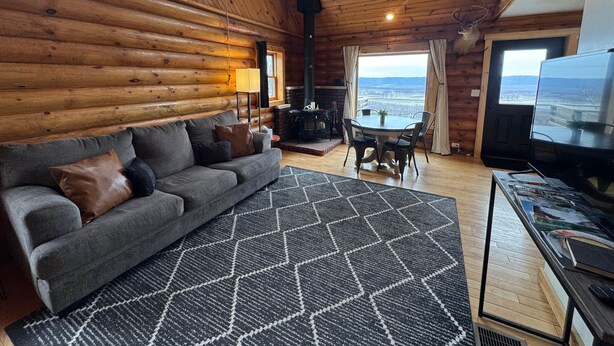 Een chaletinterieur met een bank, een eettafel, een open haard en een televisietoestel.
