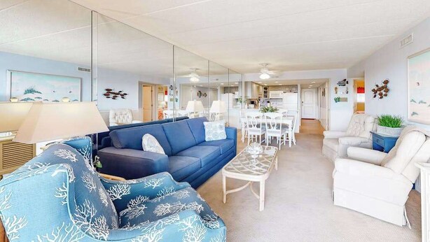 Ett vardagsrum med en soffa, fåtöljer, ett soffbord och en matplats med stolar och ett bord.