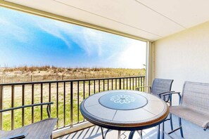 Ein Balkon mit Tisch und Stühlen, Blick auf den Strand und eine Holzlattenveranda.