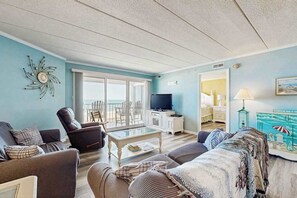 Ein Wohnzimmer mit Sofa, Sessel, Couchtisch, Fernseher und einem Gemälde.