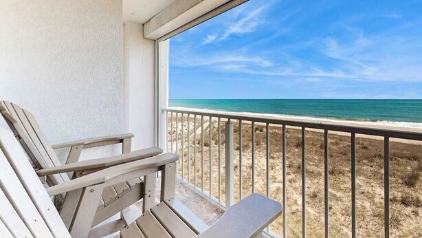 A balcony with two wooden chairs and a view of the beach. - Airy Beachfront Condo w/Great Views, Private Balcony, W/D, Shared Outdoor Pool (Ocean City)