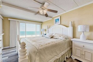 Ein Schlafzimmer mit Bett, Nachttisch, Deckenventilator, Fenster mit Meerblick und Kommode.