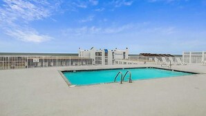 A pool area with a clear sky, a building labeled 'Vinsoles,' and a fenced deck. - Newly Updated Condo Steps from the Beach w/ Balcony, Shared Rooftop Pool (Ocean City)