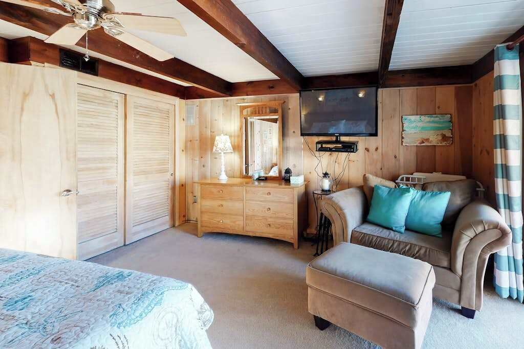 A bedroom with a bed, a dresser, a television, and a sofa.
