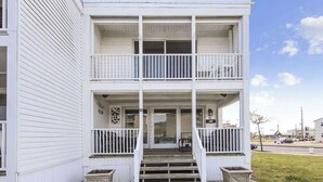 Ein zweistöckiges Gebäude mit Balkon, Veranda und einer Treppe zum Eingang.