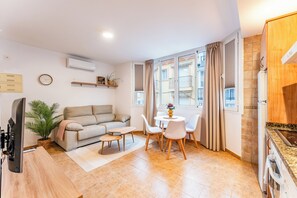 Ein Wohnzimmer mit einer Couch, einem Couchtisch und einem Fernseher. Es gibt eine Essecke mit Tisch und Stühlen.