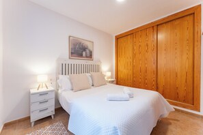 Ein Schlafzimmer mit einem Bett, Nachttischen, einem Holzschrank und einem gemusterten Teppich.