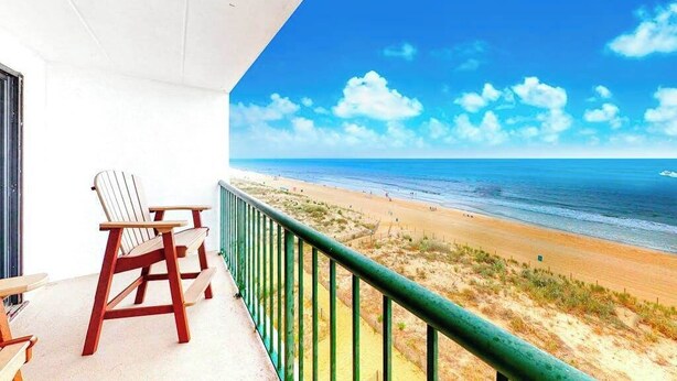 Een balkon met twee Adirondack-stoelen met uitzicht op een strand.