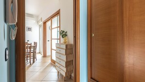 Un pasillo con una puerta de madera, un aparador de madera, una planta y un teléfono.