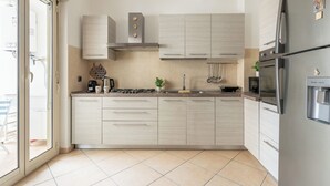 Una cocina moderna con armarios de color claro, un refrigerador de acero inoxidable y una estufa a gas.