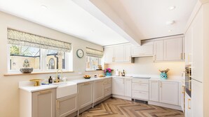 Una cucina moderna con mobili bianchi, pavimento in legno a spina di pesce e una finestra vista esterna.