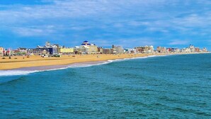 A coastal cityscape with a beach, buildings, and a clear sky. - Gorgeous & roomy condo with partial AC & full kitchen - steps from beach access (Ocean City)
