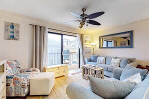Ein Wohnzimmer mit einer Couch, einem Hocker und einem Deckenventilator.