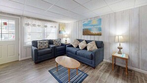 A living room with two sofas, a coffee table, a painting on the wall, and a window with blinds. - Newly remodeled, ocean block condo with balcony, central AC & W/D (Ocean City)