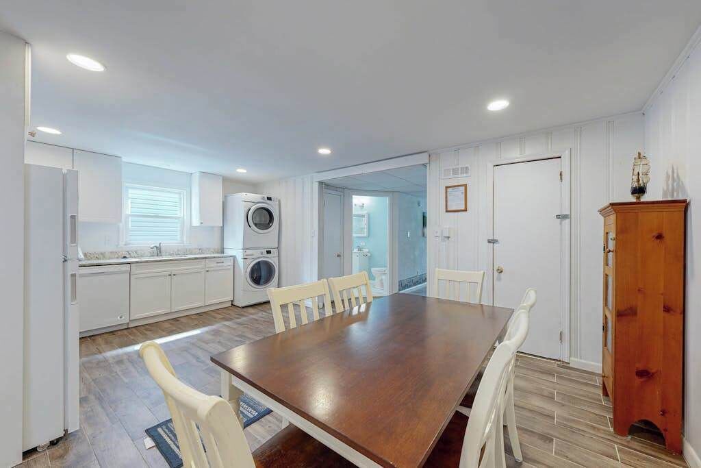 A kitchen with a washing machine, a dining table with chairs, and a cabinet.