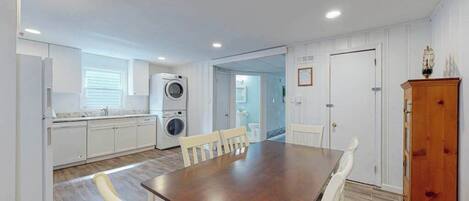 A kitchen with a washing machine, a dining table with chairs, and a cabinet.