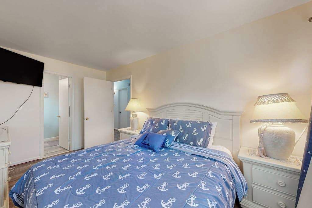 A bedroom with a bed, bedside tables, lamps, and a mirror.