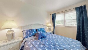 A bedroom with a bed, nightstands, lamps, a dresser, and a window with curtains. - Newly remodeled, ocean block condo with balcony, central AC & W/D (Ocean City)