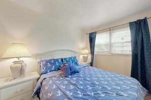 A bedroom with a bed, nightstands, lamps, a dresser, and a window with curtains. - Newly remodeled, ocean block condo with balcony, central AC & W/D (Ocean City)