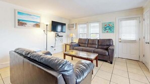 A living room with a sofa, a coffee table, a TV, and artwork on the walls. - Casa Sophia #12 (Ocean City)