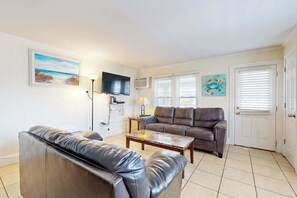 Ein Wohnzimmer mit einer Couch, einem Couchtisch, einem Fernseher und Kunstwerken an den Wänden.