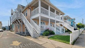 A two-story building with a balcony on the second floor, a staircase leading to the entrance, and a parking sign on the street. - Casa Sophia #12 (Ocean City)