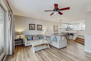 A modern living room with a sofa, coffee table, and a ceiling fan. - Newly Renovated, 3-Story Townhome with Balconies, WiFi, AC & Washer/Dryer (Ocean City)