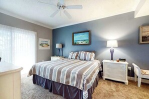 A bedroom with a bed, a nightstand, a lamp, a chair, and a ceiling fan. - Summer House 102 (Ocean City)