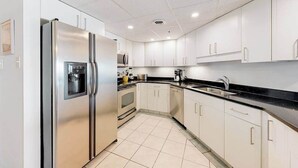 A modern kitchen with white cabinets, a stainless steel refrigerator, a microwave, and a dishwasher. - Newly updated, oceanfront condo with balcony, views & pool (Ocean City)