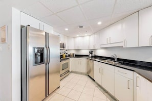 A modern kitchen with white cabinets, a stainless steel refrigerator, a microwave, and a dishwasher. - Newly updated, oceanfront condo with balcony, views & pool (Ocean City)