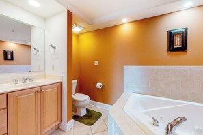 A bathroom with a bathtub, toilet, and wooden cabinets. - Well-Decorated, Ocean Block Condo w/ Fireplace, Balcony & Shared Pool/Gym (Ocean City)