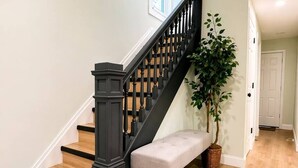 A staircase with a dark balustrade, a bench, and a potted plant. - Sleeps 10 •4BR Home •Perfect for Groups & Families (Columbus)