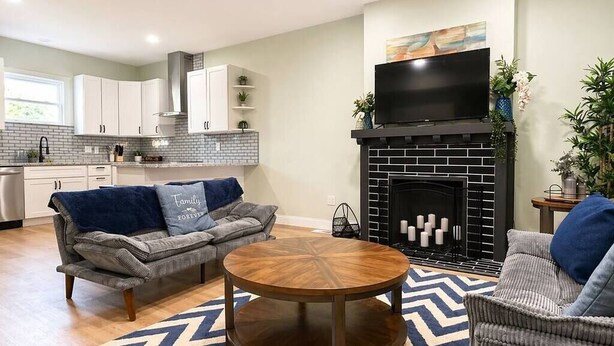 A living room with a fireplace, sofa, and round coffee table. - Sleeps 10 •4BR Home •Perfect for Groups & Families (Columbus)