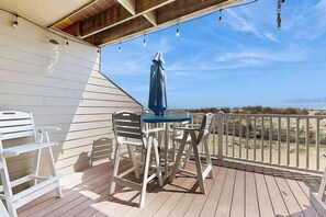 A wooden deck with a table and chairs, overlooking a beach. - Oceanfront Townhome with Multiple Decks, Direct Beach Access & WiFi (Ocean City)
