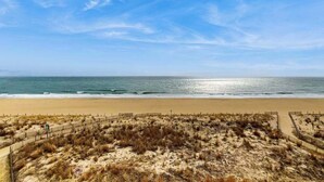Ein Strand mit einem sandigen Pfad und Dünen, der zum Meer führt.