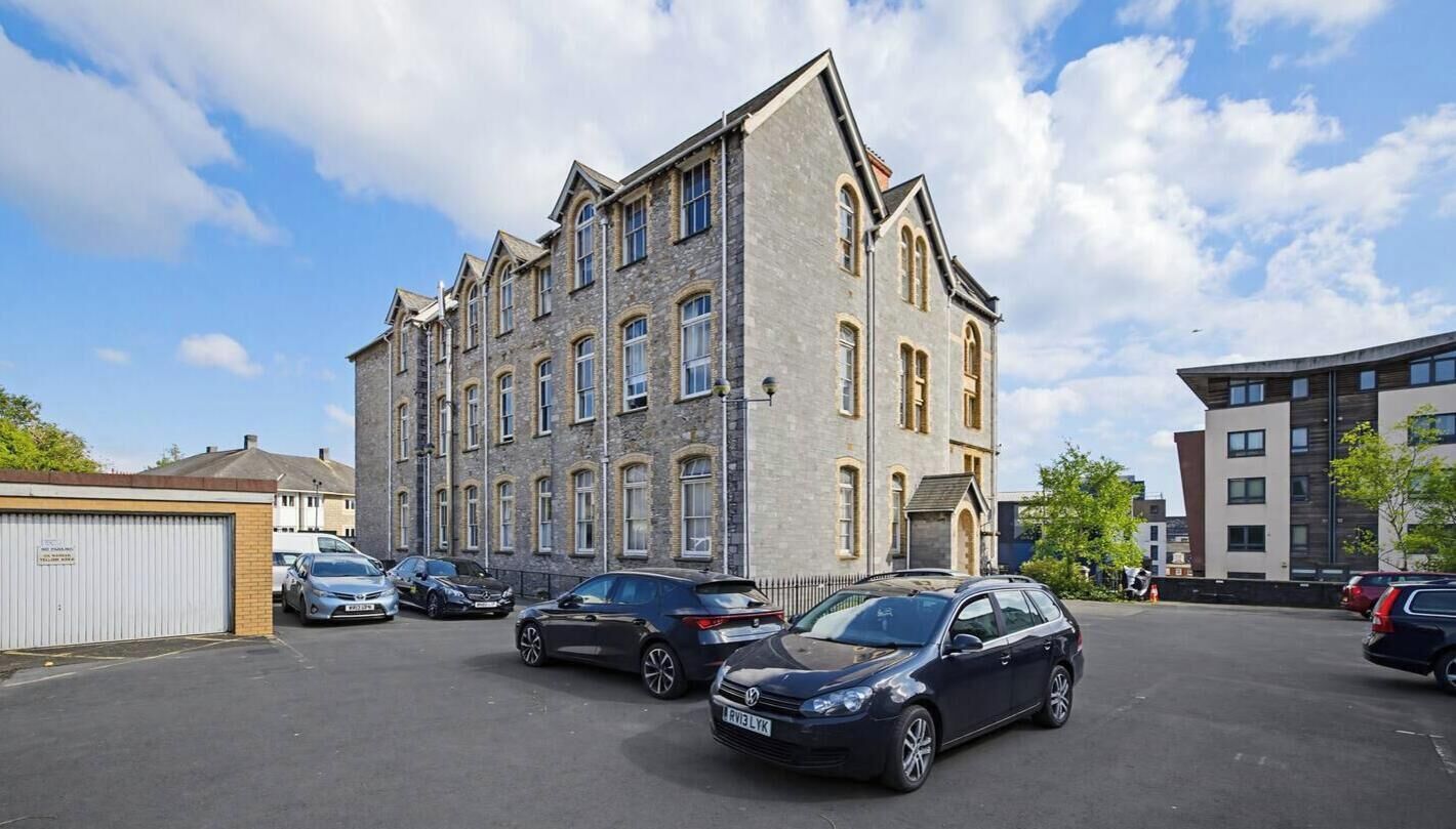 A multi-story building with a parking lot in front.