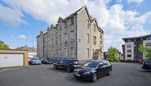 Un immeuble à plusieurs étages avec un parking situé à l’avant.