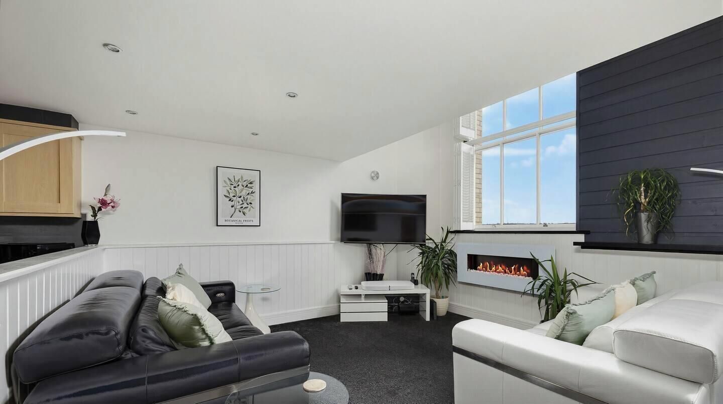 A modern living room with a fireplace, a flat-screen TV, and a sofa.