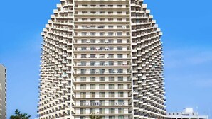 Ein Hochhaus mit markantem, eckigem Design, das mehrere Balkone und eine einheitliche Fassade aufweist.