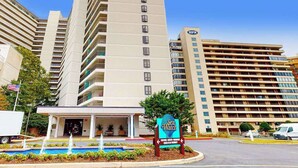 A multi-story hotel with a pool area and a sign for 'Sea Watch.' - Sunny coastal condo with balcony, pools, gym, central AC & tennis (Ocean City)