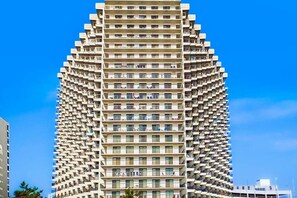 A high-rise building with a unique architectural design, featuring multiple balconies and a uniform facade. - Wonderful beachfront condo with balcony, pools, gym, sauna & game room (Ocean City)