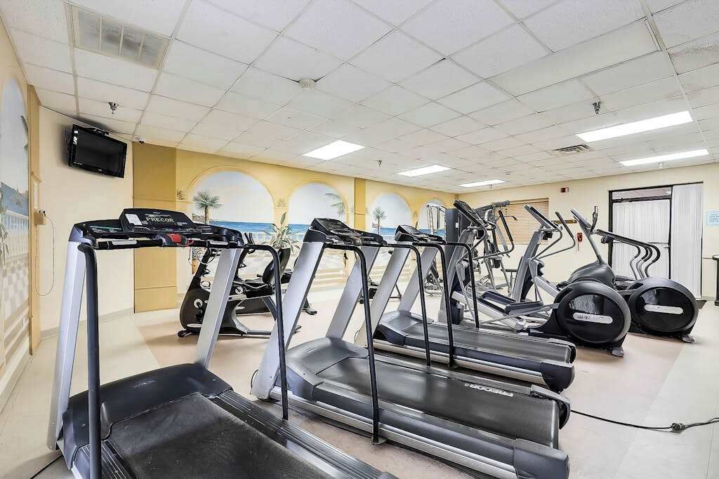 Una palestra con diverse tapis roulant, cyclette e macchine ellittiche.