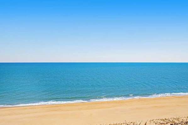 Une plage avec une eau d’un bleu limpide et un rivage sablonneux.