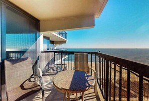 Un balcon avec une table et des chaises, donnant sur une étendue d’eau.
