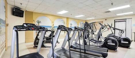 A gym with multiple treadmills, stationary bikes, and elliptical machines.