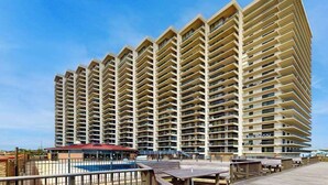A high-rise hotel with multiple balconies, a pool area, and a boardwalk. - Sunny beach condo with balcony, game room, pools, sauna & gym (Ocean City)