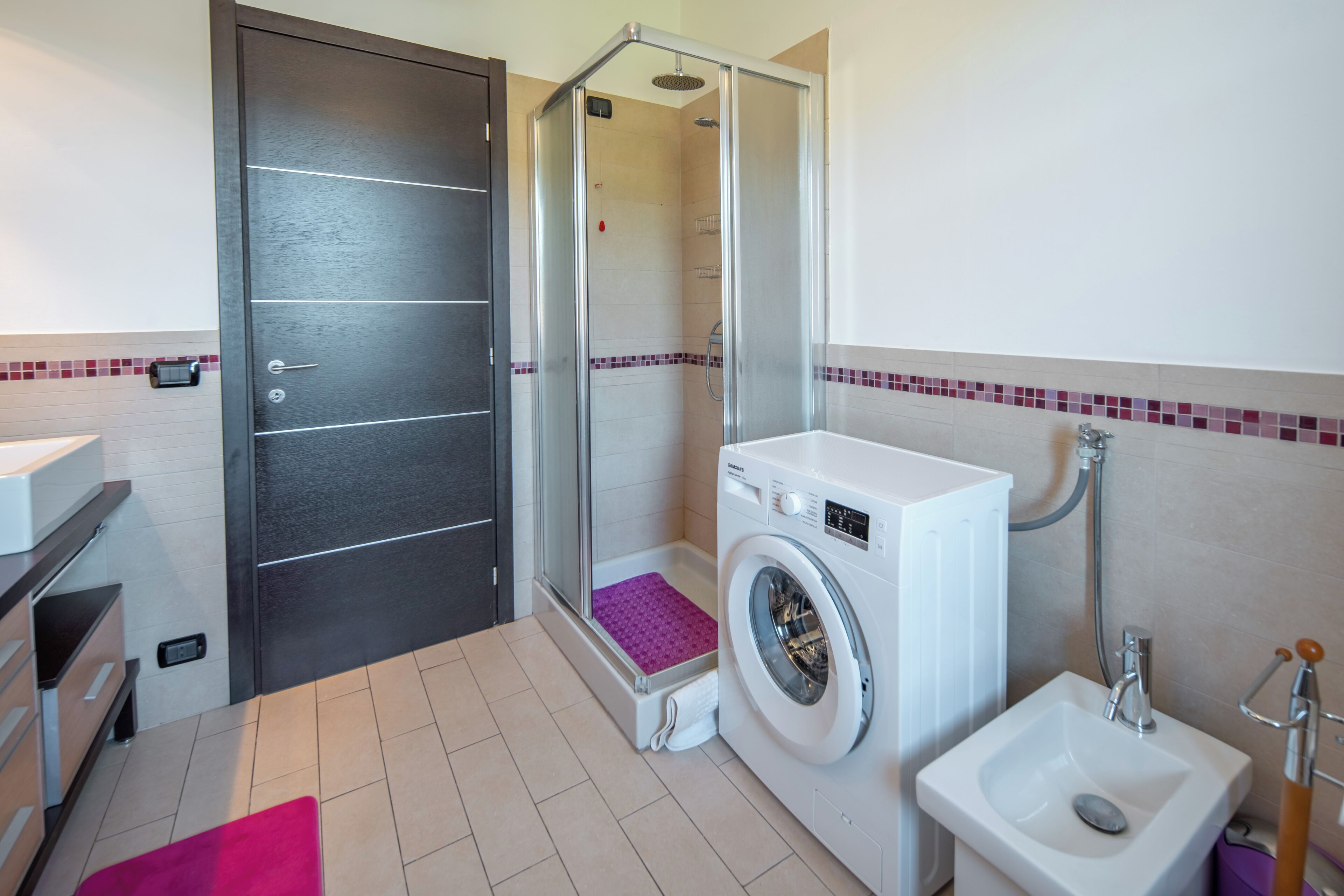 Un baño moderno con ducha, lavadora, inodoro y lavamanos.