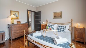 A neatly arranged bedroom with a bed, bedside tables, a dresser, and a door leading to another room. - Ca' Felicina - Two Bedroom Apartment, Sleeps 4 (Alba)