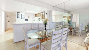 Una cocina moderna con armarios blancos, una mesa de comedor de vidrio y una isla central.